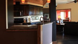 A modern kitchen with dark cabinets, a microwave, and a sink. There is a dining area with a table and chairs.
