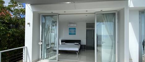 Un balcone moderno e spazioso con una porta vetrata che dà su una camera da letto.