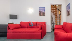 Un salon avec un canapé rouge, un téléviseur et un escalier.