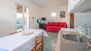Une cuisine compacte avec une table à manger, un canapé rouge et un mur recouvert de carreaux.