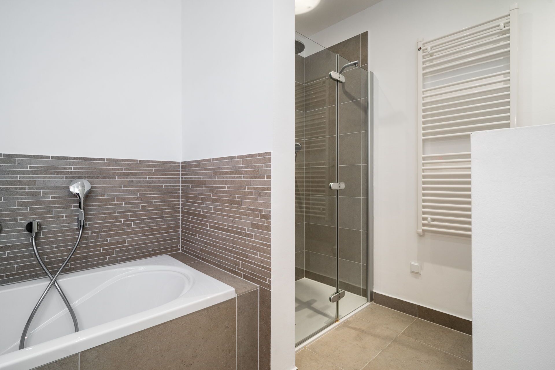Un baño con bañera, ducha y zona de ducha con paredes de vidrio.