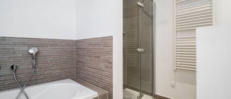 Un baño con bañera, ducha y zona de ducha con paredes de vidrio.