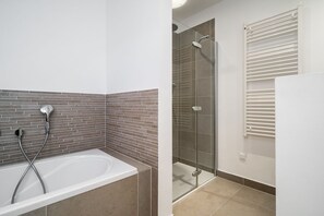 A bathroom with a bathtub, shower, and a glass-enclosed shower area.
