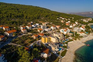 An aerial view of a coastal town with buildings, a beach, and a clear view of the sea.
