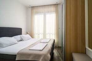 A hotel room with a bed, a bedside table, and a window with curtains.