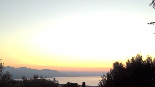 A swimming pool with a wooden deck, surrounded by trees and a view of distant mountains during sunset. - Country Cottage / Gite - Campofelice di roccella (Campofelice di Roccella)