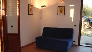 A room with a blue sofa, a floor lamp, and two framed pictures on the wall. - Country Cottage / Gite - Campofelice di roccella (Campofelice di Roccella)
