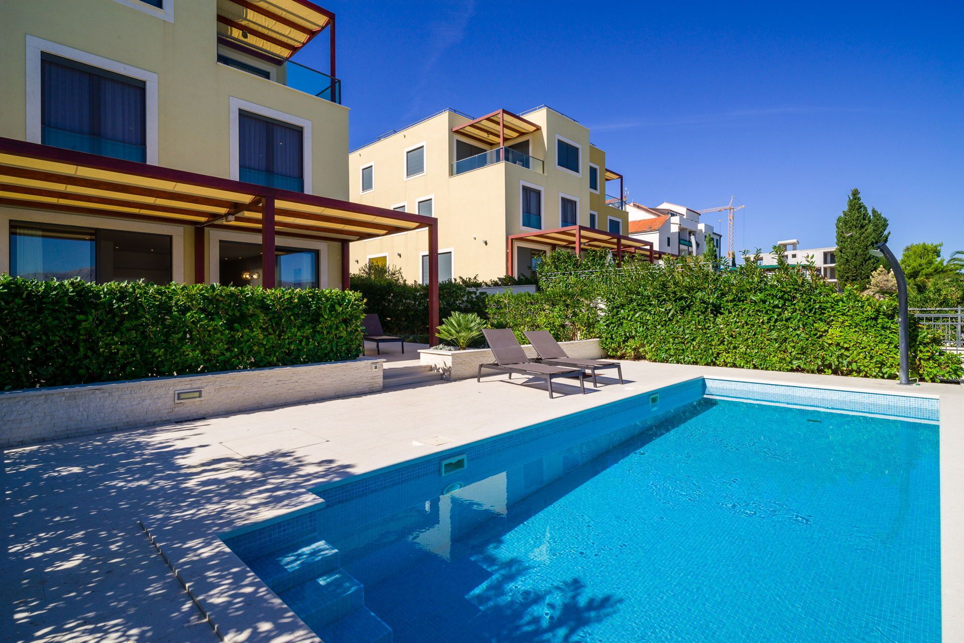 Un hôtel moderne doté d’une piscine, de chaises longues et d’un espace extérieur couvert.