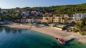 A coastal town with modern buildings, a clear beach, and a boat on the shore. - Beachfront Apartment Lemonade VI (Trogir)
