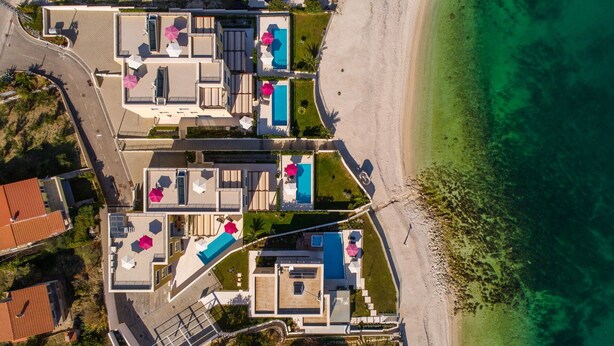 An aerial view of a coastal hotel with multiple swimming pools, a beach, and a road nearby. - Beachfront Apartment Lemonade VI (Trogir)