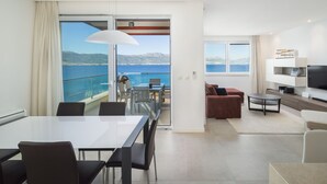 A modern hotel room with a balcony overlooking a scenic coastal view. - Beachfront Apartment Lemonade VI (Trogir)