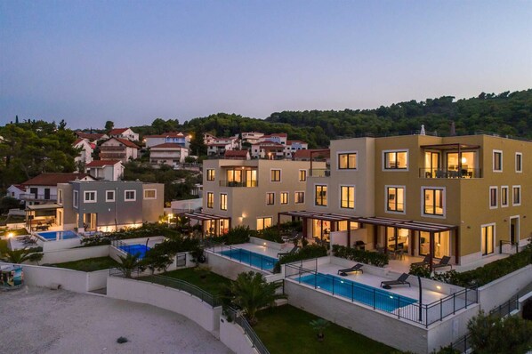 Un edificio residencial moderno con varios balcones, piscina y un jardín bien cuidado.