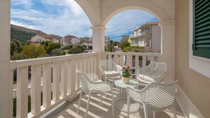 Ein Balkon mit weißen Korbmöbeln und Blick auf eine Wohngegend.