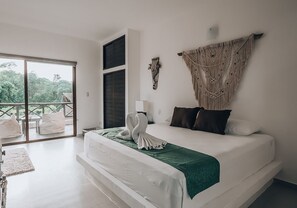 A modern bedroom with a large bed, a balcony, and a macrame wall hanging. - Xcacel Dreams Jungle Suites & Spa (Tulum)