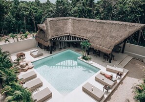 A pool area with lounge chairs and a thatched-roof structure.