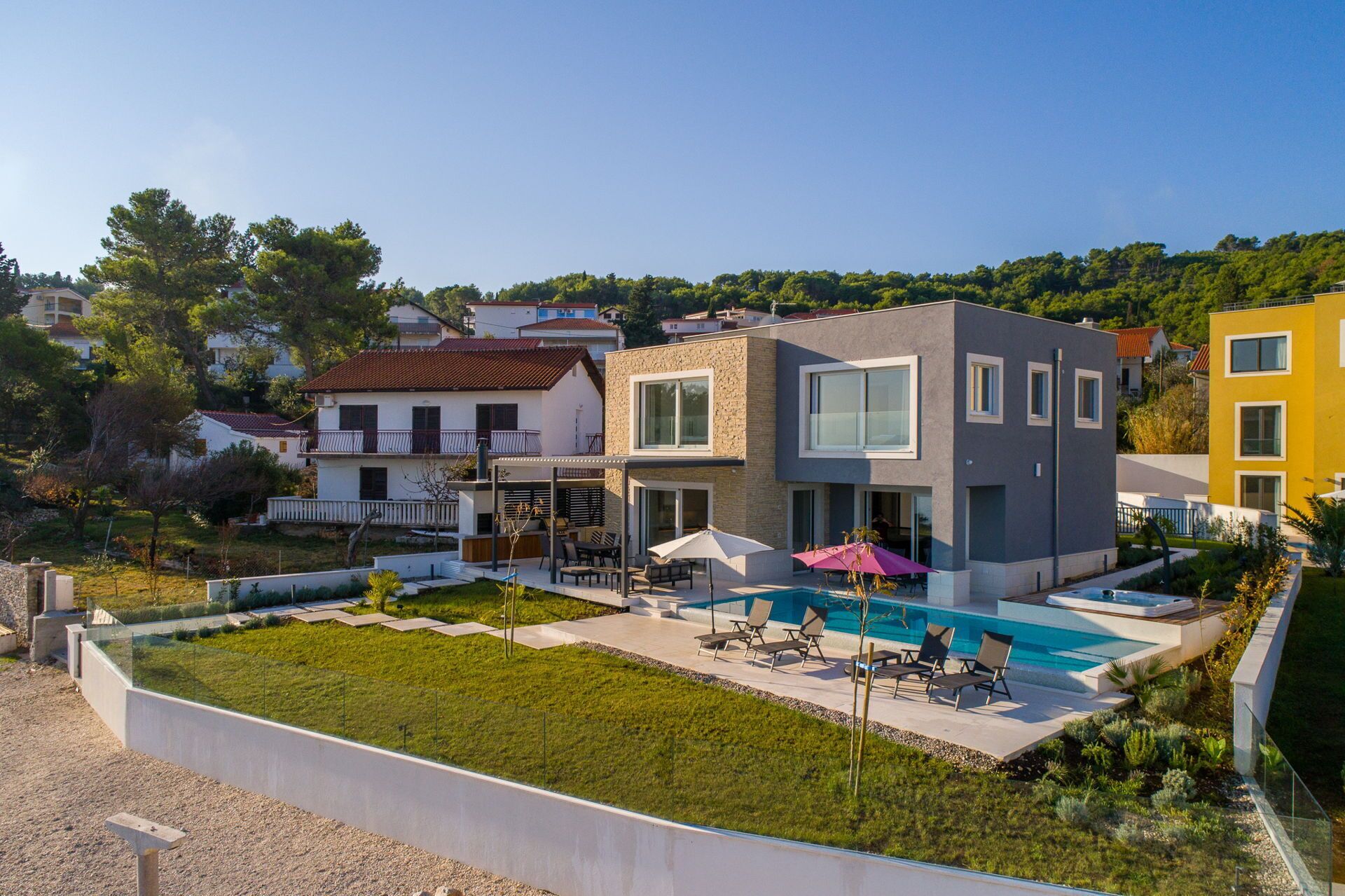 A modern two-story house with a swimming pool, outdoor seating, and a well-maintained garden.