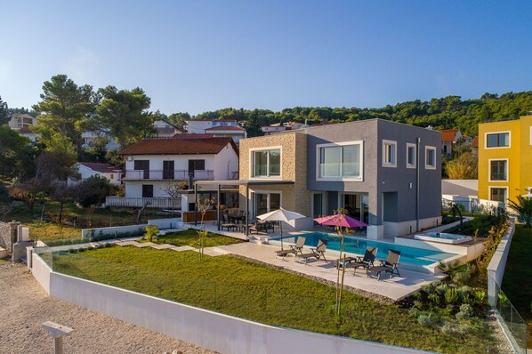 Uma casa moderna de dois andares com piscina, área de estar externa e um jardim bem cuidado.