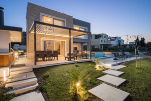 Uma casa moderna com alpendre, área de estar externa e piscina.
