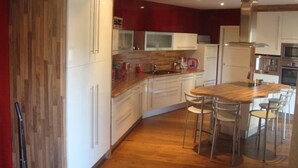 A modern kitchen with white cabinets, a wooden countertop, and a central island with chairs.
