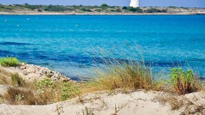 A coastal landscape with clear blue water, sandy beach, and a white building in the distance. - Apartment On the Beaches of Gallipoli (Gallipoli)