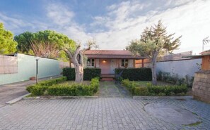 Ein Haus mit Ziegeldach, gepflasterter Auffahrt und einem gepflegten Garten mit Hecken und Bäumen.
