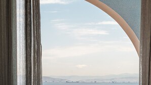 Ein Balkon mit Blick auf das Meer, einem weißen Tisch und einem weißen Plastikstuhl.