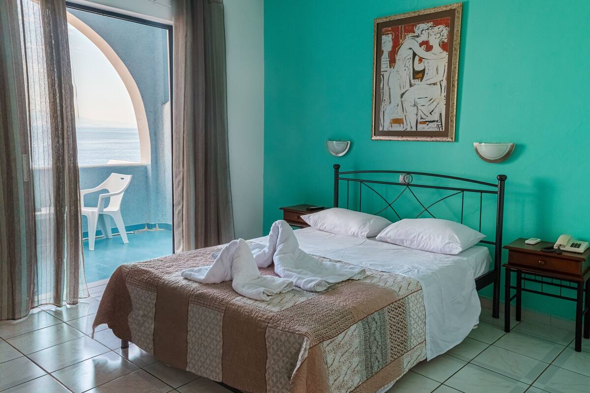 Une chambre d’hôtel avec un lit, une table de chevet, une chaise et un tableau au mur.
