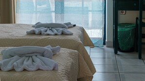 Ein Hotelzimmer mit zwei Betten, einem großen Fenster mit Aussicht, einem Sessel und einem Mülleimer.