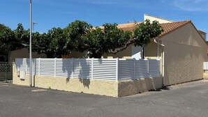 A building with a beige exterior, a white fence, and a tiled roof.