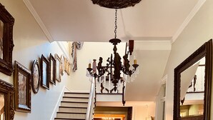 Una imponente escalera de madera que conduce a un comedor con candelabro.