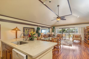 A spacious kitchen with a large island, a dining area with wooden chairs, and a ceiling fan. - 2/2 OCEAN VIEW with AC,  Poipu Beach Condo Resort, Kiahuna, Pool, Gym, Courts (Koloa)
