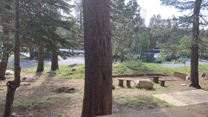 Ett skogsområde med en grusstig, träbänkar och ett trästaket.
