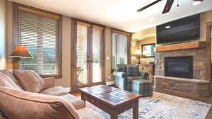 A living room with a fireplace, a sofa, a coffee table, and a television mounted on the wall.