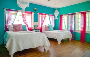 A room with two beds, teal walls, and pink curtains.