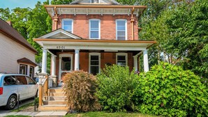 A two-story brick house with a front porch, columns, and a garage. - The Copper Penny House - Walking Distance To The Falls! (Niagara Falls)