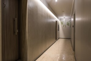 A long, narrow hallway with a wooden door on the left and a series of doors on the right. The floor is tiled, and the walls are painted in a light color. - AthinA STREETAPARTMENTS (Athens)