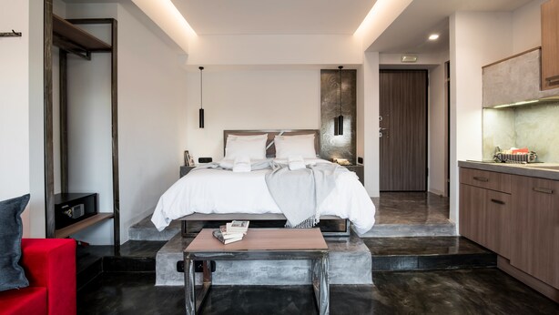 A modern bedroom with a bed, bedside table, and a small kitchen area. - AthinA STREETAPARTMENTS (Athens)