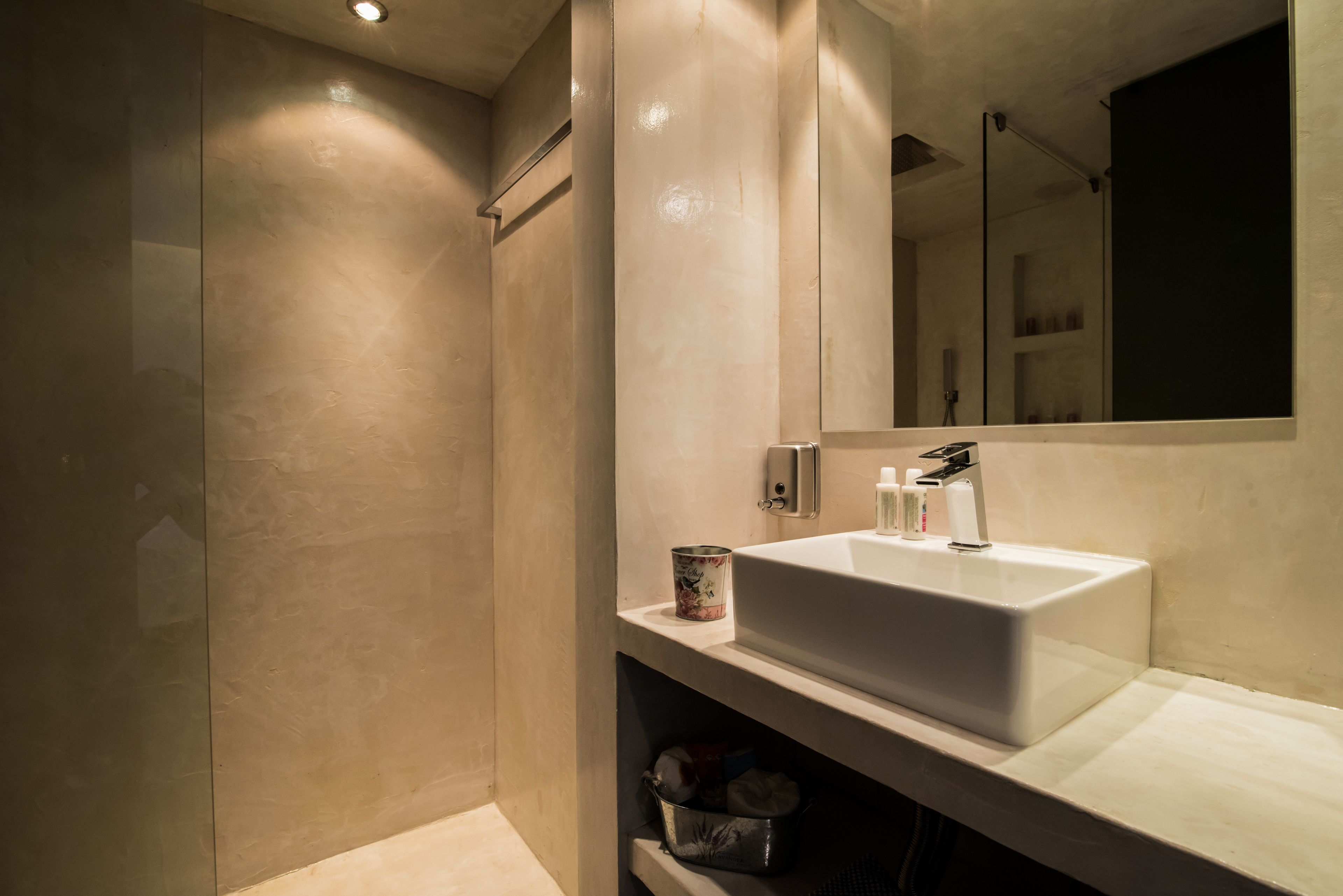 Un bany modern amb un mirall gran, un lavabo blanc i una zona de dutxa.