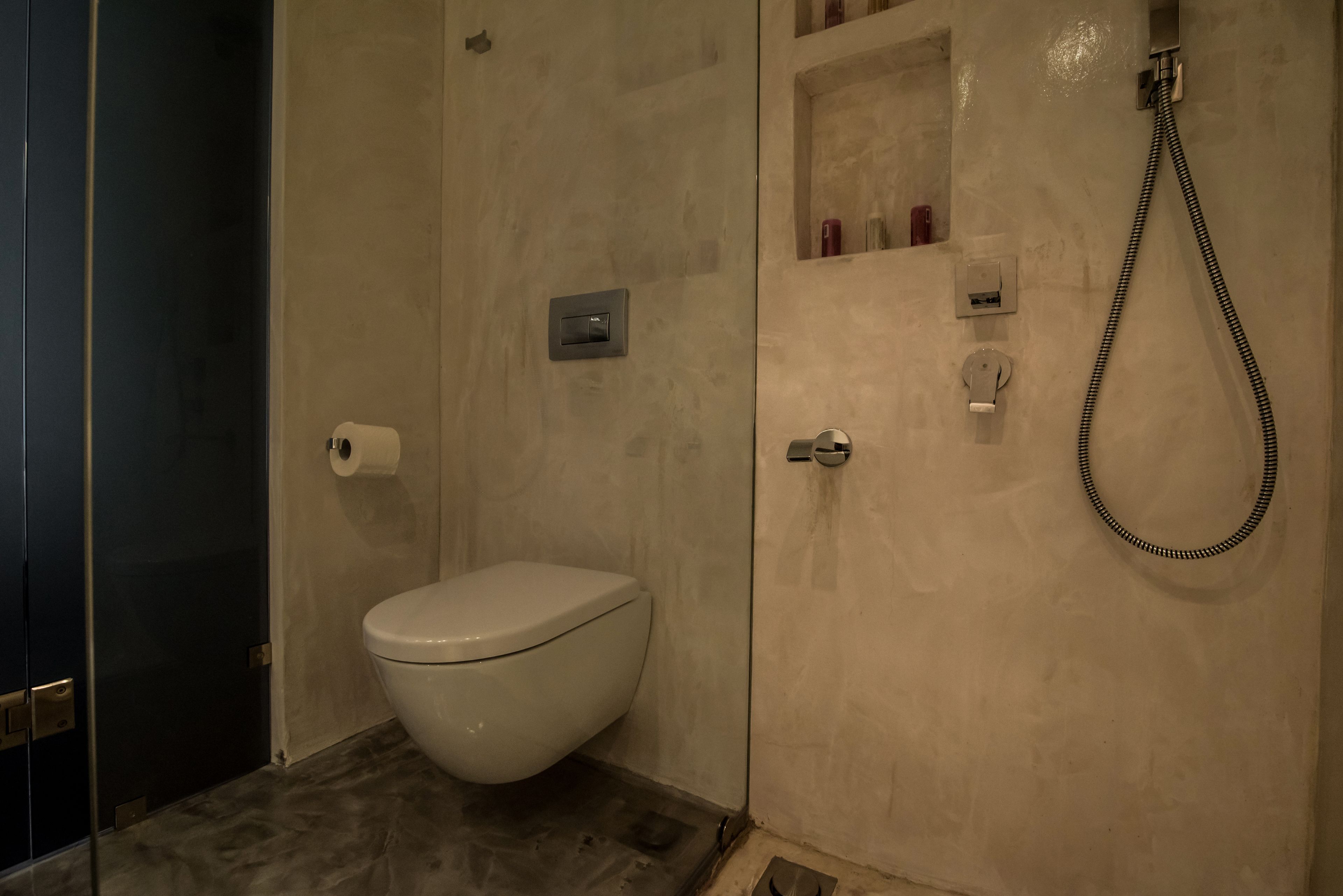 Un bagno moderno con il water, doccia e scaffali contenitori.