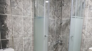 A modern bathroom with a glass-enclosed shower, a toilet, and a sink.