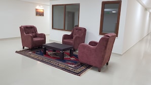 Una habitación con dos sillones, una mesita y una alfombra estampada sobre suelo de baldosas.