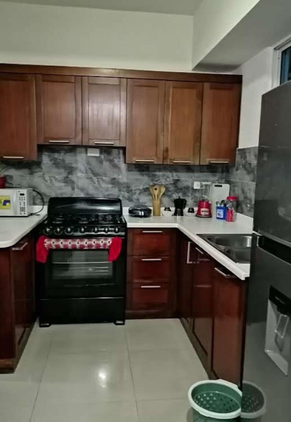 A kitchen with wooden cabinets, a stove, a microwave, and a refrigerator.