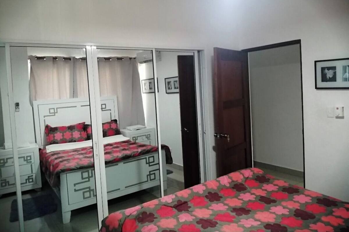 Quarto com cama, guarda-roupa e mesa de cabeceira.