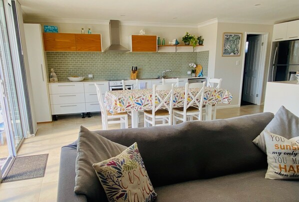 A modern kitchen with white cabinets, a tiled backsplash, and a dining area with a table set for four.