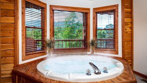 A hot tub in a corner with wooden walls and windows. - Gatlinburg Log Cabin, Amazing Views Hot Tub, Theater Room, Internet Free Tickets (Gatlinburg)