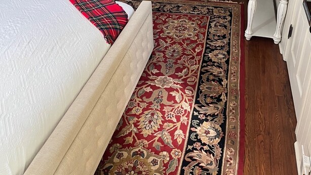 A bedroom with a bed, two armchairs, a small table, a radiator, and a window.