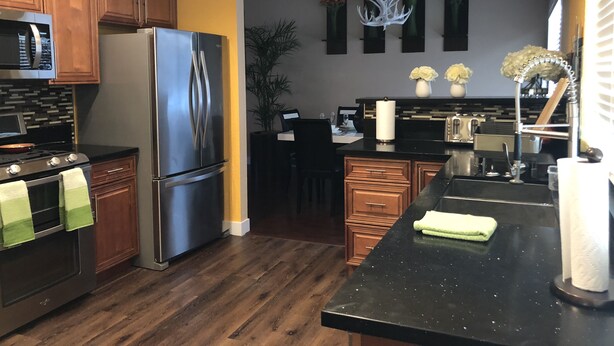Una cocina moderna con electrodomésticos de acero inoxidable, armarios de madera y encimera negra.