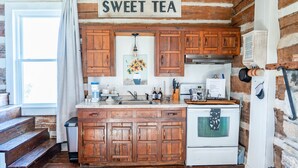 A rustic kitchen with wooden cabinets, a white stove, and a sign that reads "SWEET TEA".