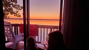 A room with a large window overlooking a body of water during sunset. - Large Cottage:  Private Beach/Stunning Sunsets/Kayaks/Fire Pit (Swanton)