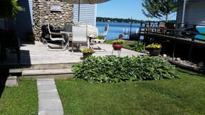 Un patio con mobiliario exterior, un muro de piedra y vista a un lago.